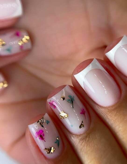 close up of white french tip and abstract flower design on square nails