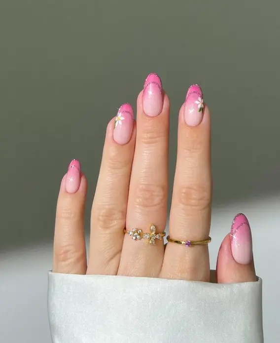 short oval nails with pink glitter ombré french tip and white flower design
